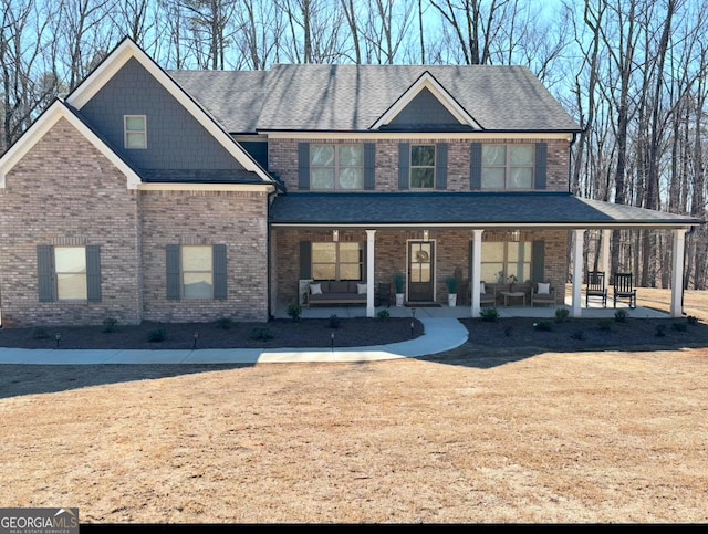 view of front of property featuring brick siding, a shingled roof, and covered porch