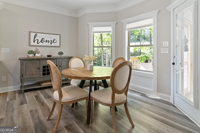 dining space featuring baseboards, ornamental molding, and light wood finished floors