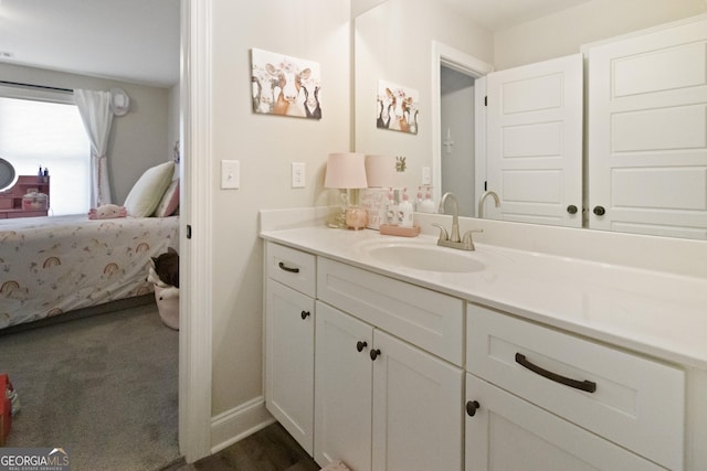 bathroom with baseboards, wood finished floors, vanity, and ensuite bathroom