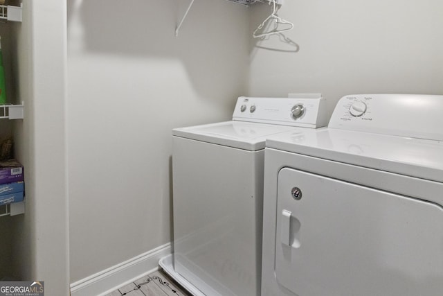 clothes washing area with separate washer and dryer, baseboards, and laundry area