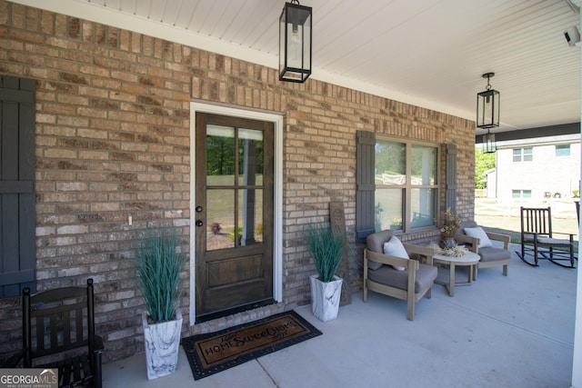 view of exterior entry featuring brick siding and a porch