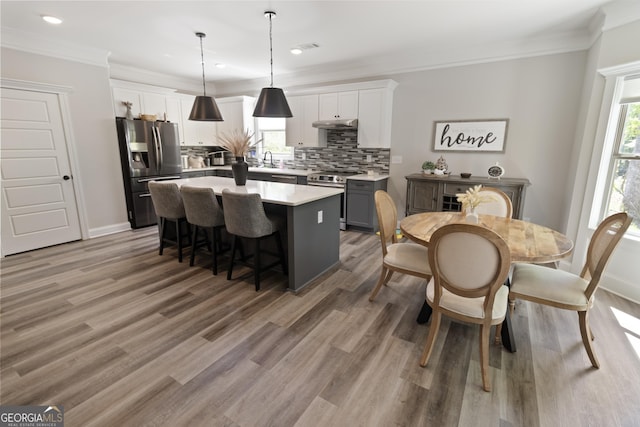 kitchen featuring stainless steel appliances, light wood-type flooring, a kitchen island, tasteful backsplash, and a breakfast bar area