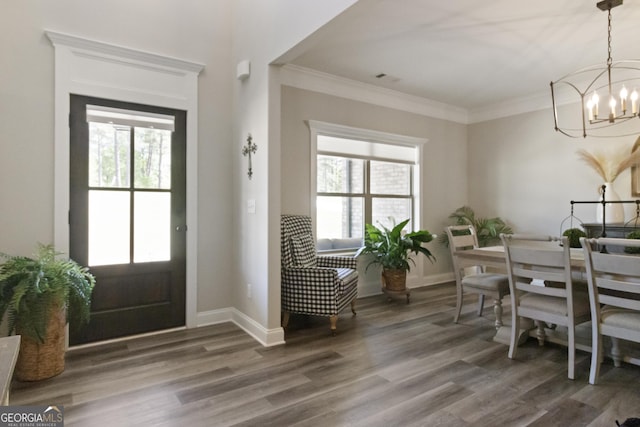 foyer entrance with plenty of natural light, crown molding, wood finished floors, and an inviting chandelier