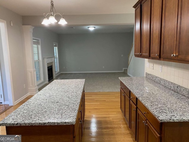 1295 Leisure Lake Dr, Lawrenceville, GA 30044 - kitchen featuring tasteful backsplash, a center island, decorative light fixtures, light wood-type flooring, and light stone counters