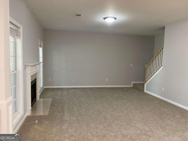 1295 Leisure Lake Dr, Lawrenceville, GA 30044 - unfurnished living room featuring baseboards, visible vents, a fireplace with flush hearth, stairs, and carpet flooring