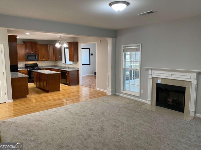 1295 Leisure Lake Dr, Lawrenceville, GA 30044 - kitchen with visible vents, a center island, open floor plan, light colored carpet, and black appliances