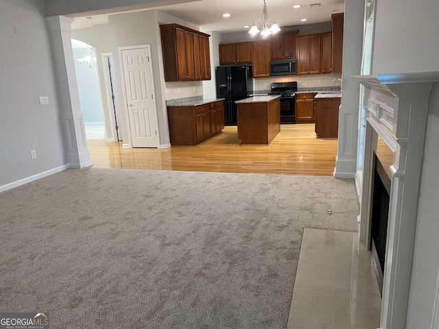 1295 Leisure Lake Dr, Lawrenceville, GA 30044 - kitchen featuring a notable chandelier, black appliances, open floor plan, decorative backsplash, and light colored carpet