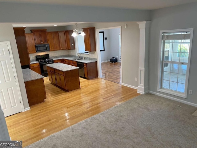 1295 Leisure Lake Dr, Lawrenceville, GA 30044 - kitchen featuring light wood finished floors, a kitchen island, black appliances, brown cabinets, and backsplash