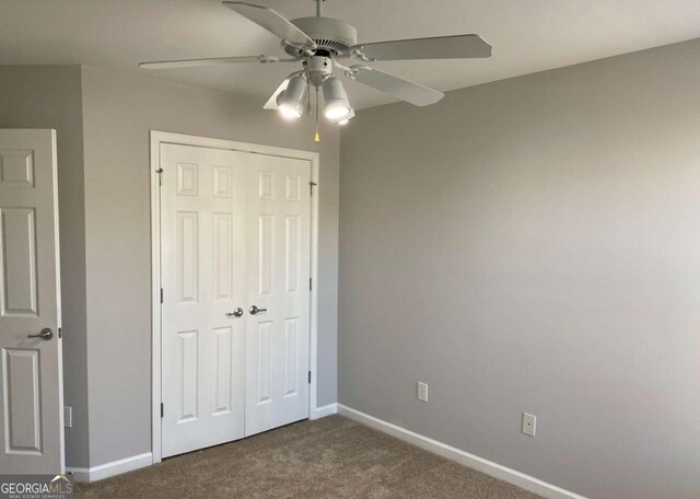 1295 Leisure Lake Dr, Lawrenceville, GA 30044 - unfurnished bedroom featuring a closet, baseboards, ceiling fan, and dark carpet