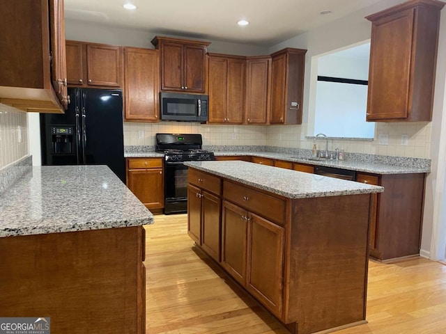 1295 Leisure Lake Dr, Lawrenceville, GA 30044 - kitchen with black appliances, light stone counters, light wood finished floors, and a sink