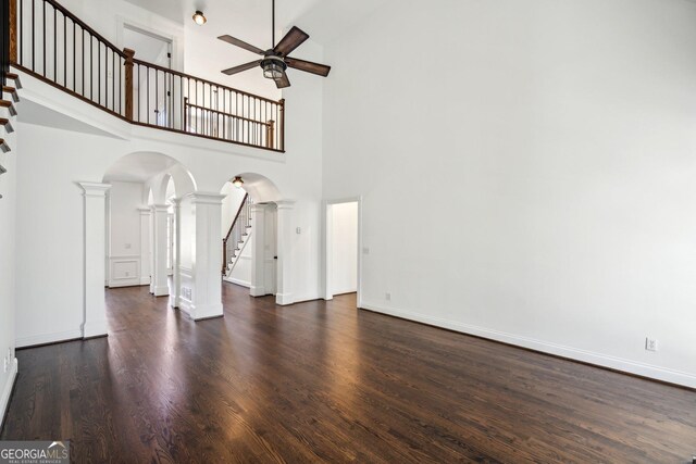 8625 Anchor On Lanier Ct, Gainesville, GA 30506 - unfurnished living room with arched walkways, ceiling fan, stairway, a towering ceiling, and decorative columns