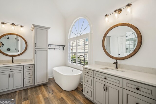 8625 Anchor On Lanier Ct, Gainesville, GA 30506 - bathroom with wood finished floors, a stall shower, a freestanding tub, vaulted ceiling, and two vanities