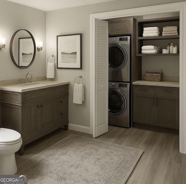 8625 Anchor On Lanier Ct, Gainesville, GA 30506 - bathroom with stacked washing machine and dryer, wood finished floors, vanity, toilet, and baseboards
