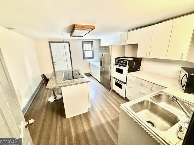 3810 Galloway Dr NE, Roswell, GA 30075 - kitchen featuring light wood finished floors, a sink, range, a breakfast bar area, and a kitchen island