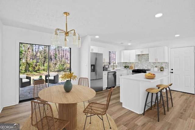 kitchen with light wood finished floors, light countertops, decorative backsplash, appliances with stainless steel finishes, and a sink