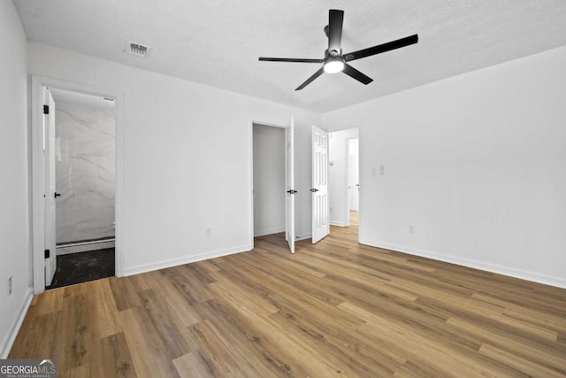 unfurnished bedroom with a baseboard radiator, wood finished floors, visible vents, and baseboards