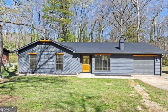 view of front of property featuring concrete driveway, an attached garage, a front yard, and a chimney
