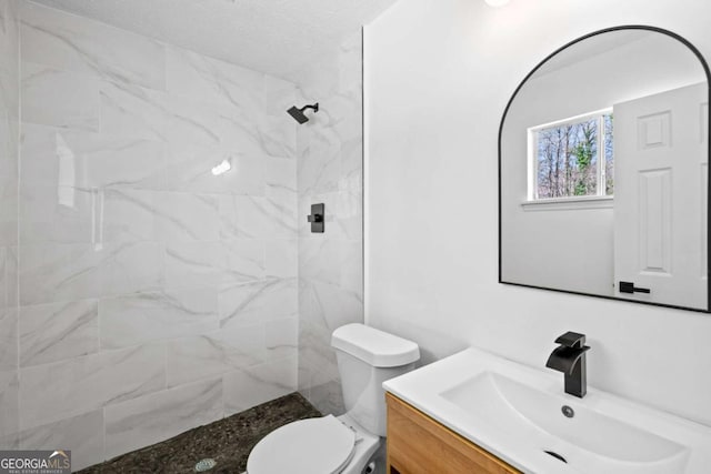 bathroom featuring vanity, toilet, and a tile shower
