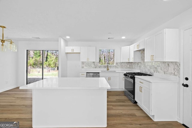 kitchen featuring plenty of natural light, backsplash, range with gas cooktop, and a sink