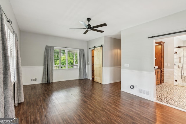 11637 Brown Bridge Rd, Covington, GA 30016 - unfurnished bedroom featuring a barn door, wood finished floors, a wainscoted wall, and ceiling fan
