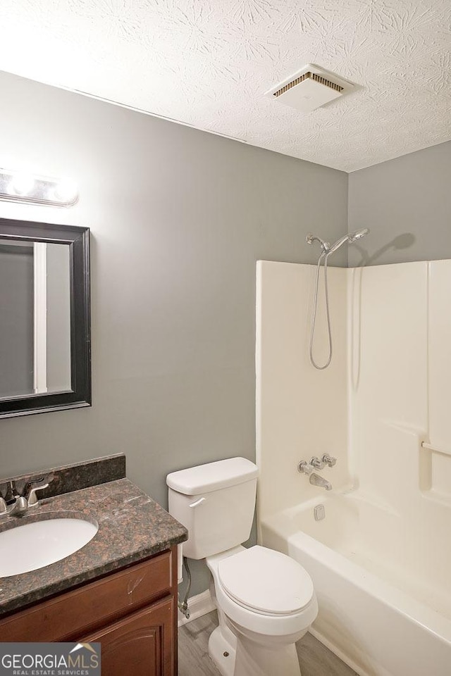 full bathroom with toilet, vanity, a textured ceiling, and shower / bathtub combination