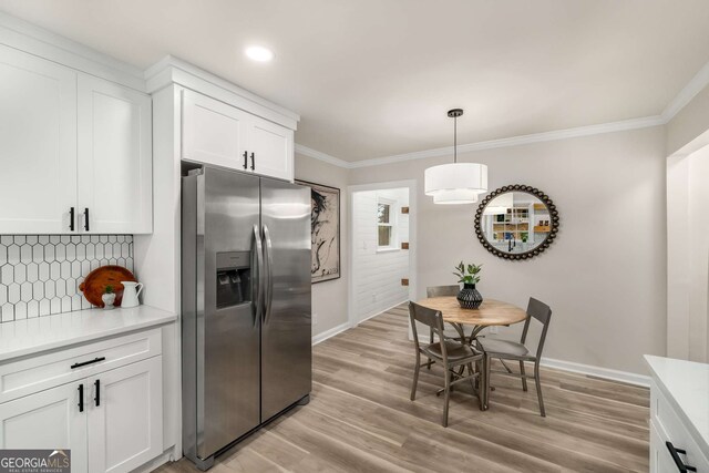 kitchen with white cabinetry, stainless steel fridge with ice dispenser, backsplash, and ornamental molding