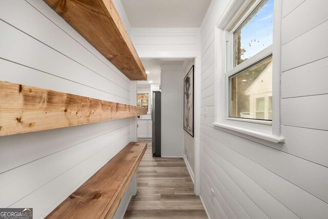 hall with wooden walls and light wood-style flooring