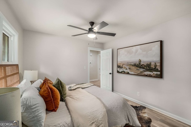 bedroom featuring a ceiling fan, baseboards, and wood finished floors