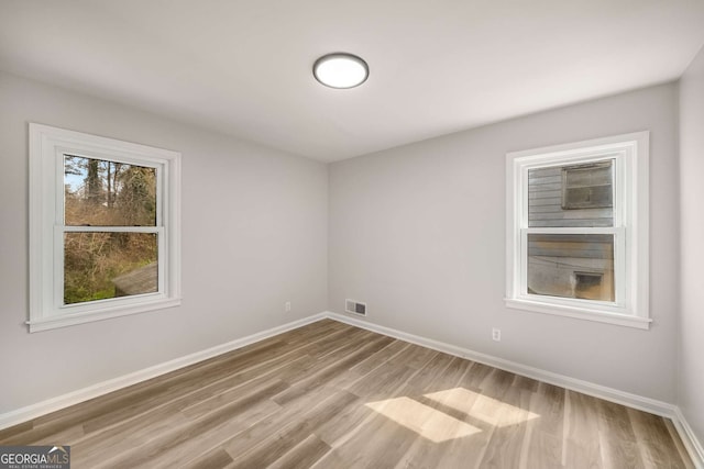 empty room featuring visible vents, baseboards, and wood finished floors