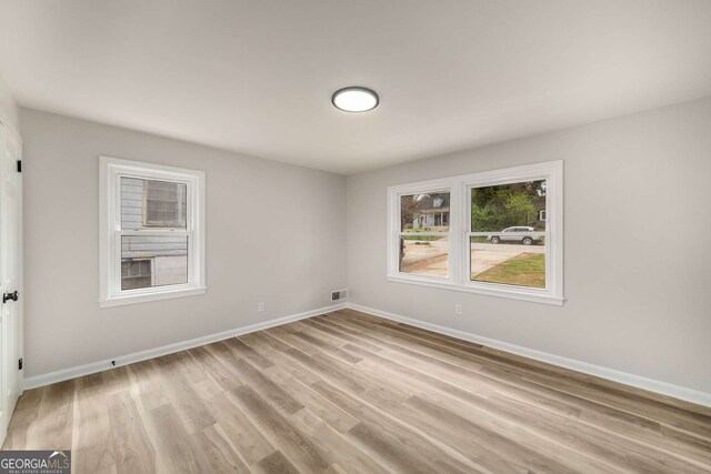 unfurnished room with visible vents, light wood-style floors, and baseboards