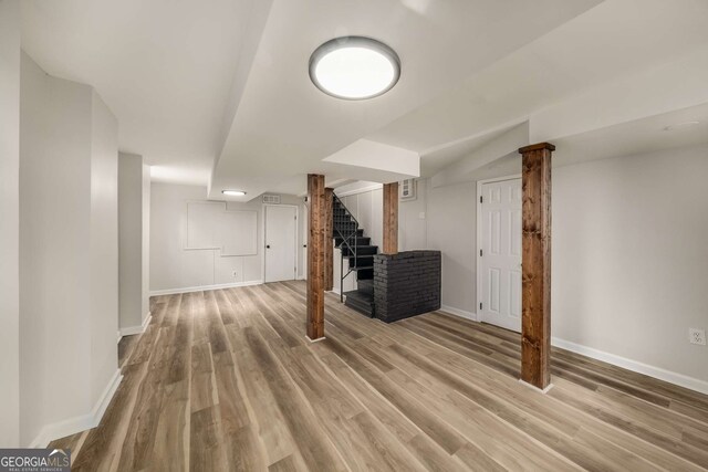 finished below grade area with light wood-type flooring, stairs, and baseboards