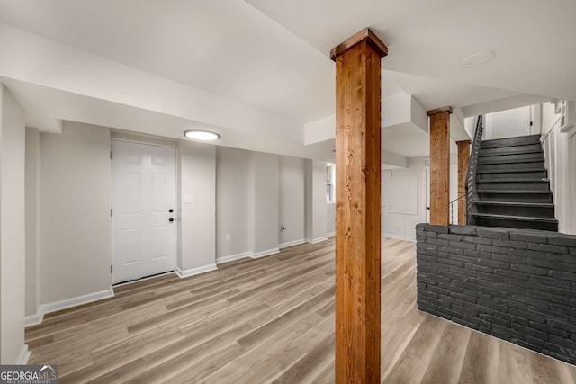 finished below grade area featuring stairway, baseboards, and wood finished floors