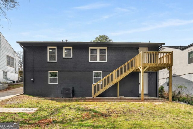 rear view of house featuring stairs, a yard, and a wooden deck