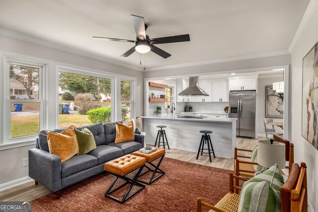 living room with plenty of natural light, light wood-type flooring, and ornamental molding