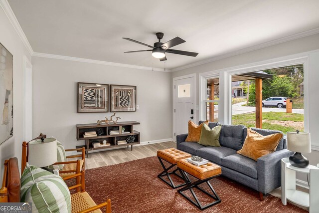 living area featuring ornamental molding, wood finished floors, baseboards, and ceiling fan