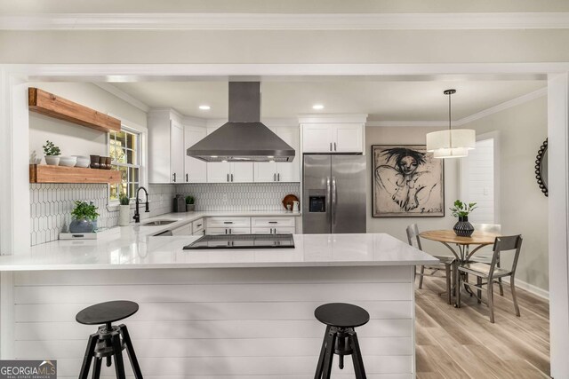 kitchen featuring island exhaust hood, a sink, a kitchen breakfast bar, crown molding, and stainless steel fridge with ice dispenser