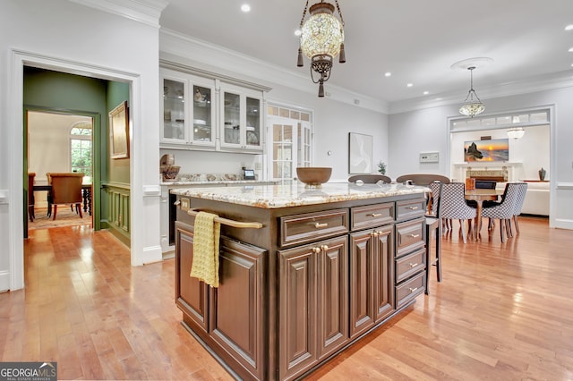 1575 Oak Mountain Rd, Shiloh, GA 31826 - kitchen featuring light wood-style flooring, decorative light fixtures, a fireplace, a kitchen island, and glass insert cabinets
