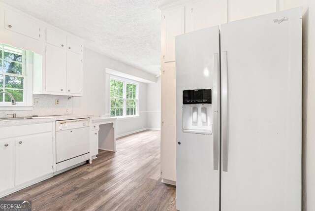 kitchen featuring a sink, white appliances, light countertops, a textured ceiling, and wood finished floors