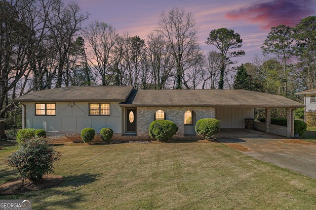 view of front facade with brick siding, a lawn, board and batten siding, and concrete driveway