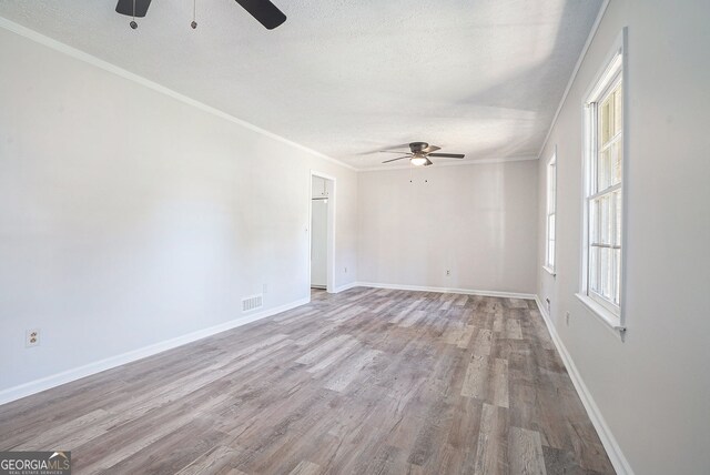 spare room with a ceiling fan, wood finished floors, visible vents, and a textured ceiling