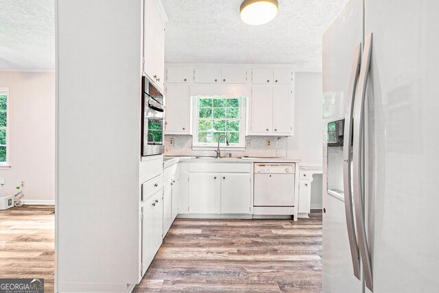 kitchen featuring stainless steel appliances, light wood-style floors, light countertops, a sink, and a textured ceiling