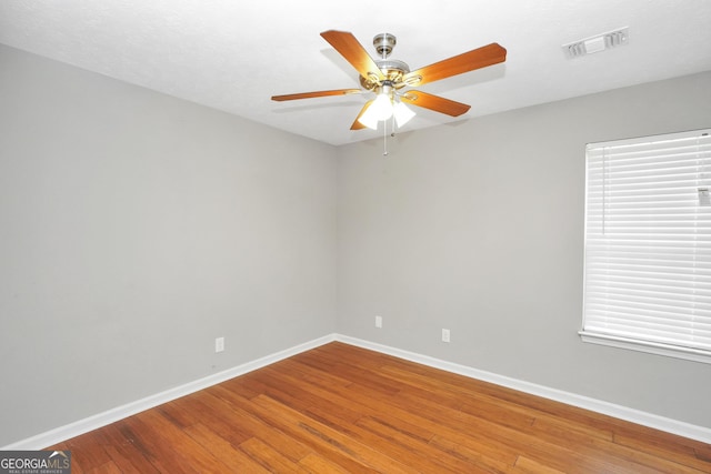 empty room with baseboards, a ceiling fan, visible vents, and wood-type flooring
