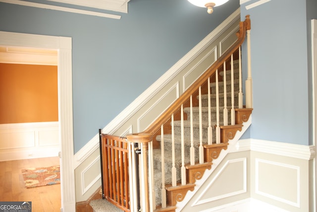 3348 Summit Turf Ln, Snellville, GA 30078 - stairway featuring wainscoting, a decorative wall, and wood finished floors
