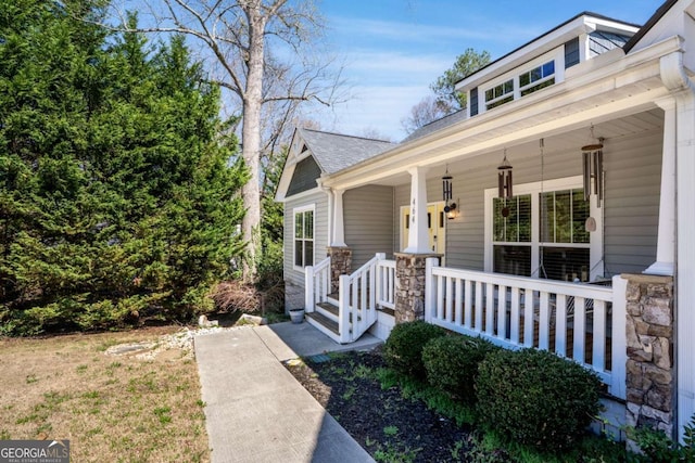 view of front of home with stone siding, a porch, and a shingled roof