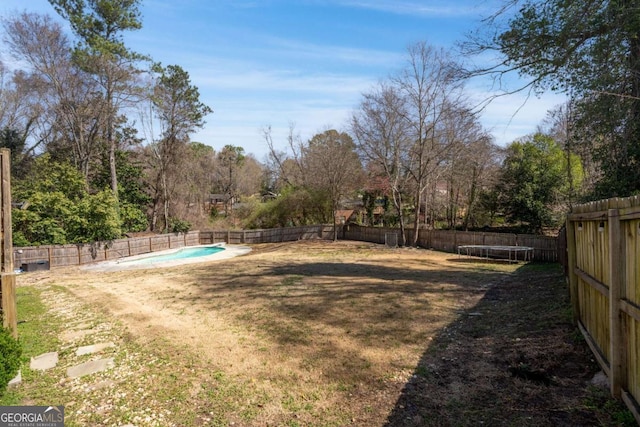 view of yard featuring a trampoline, a fenced backyard, and a fenced in pool