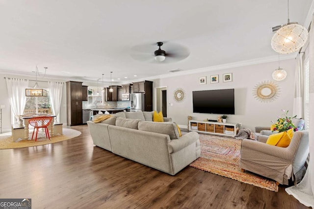 living room with dark wood finished floors, crown molding, a ceiling fan, and visible vents