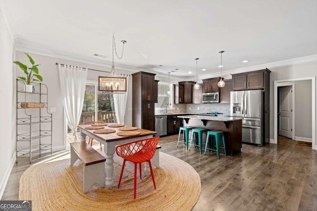 dining space with wood finished floors, baseboards, recessed lighting, crown molding, and a notable chandelier