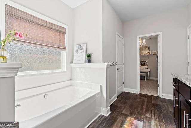 bathroom featuring vanity, a bath, wood finished floors, and baseboards