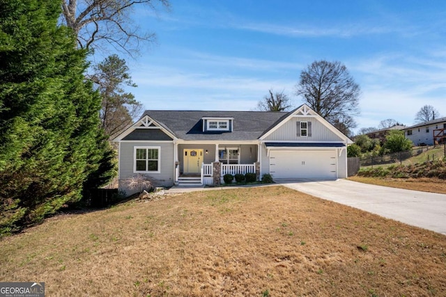view of front facade with a porch, concrete driveway, a front yard, and fence