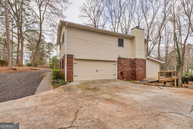 1417 Hickory Dr SW, Lilburn, GA 30047 - view of side of property featuring driveway, brick siding, an attached garage, a chimney, and a deck